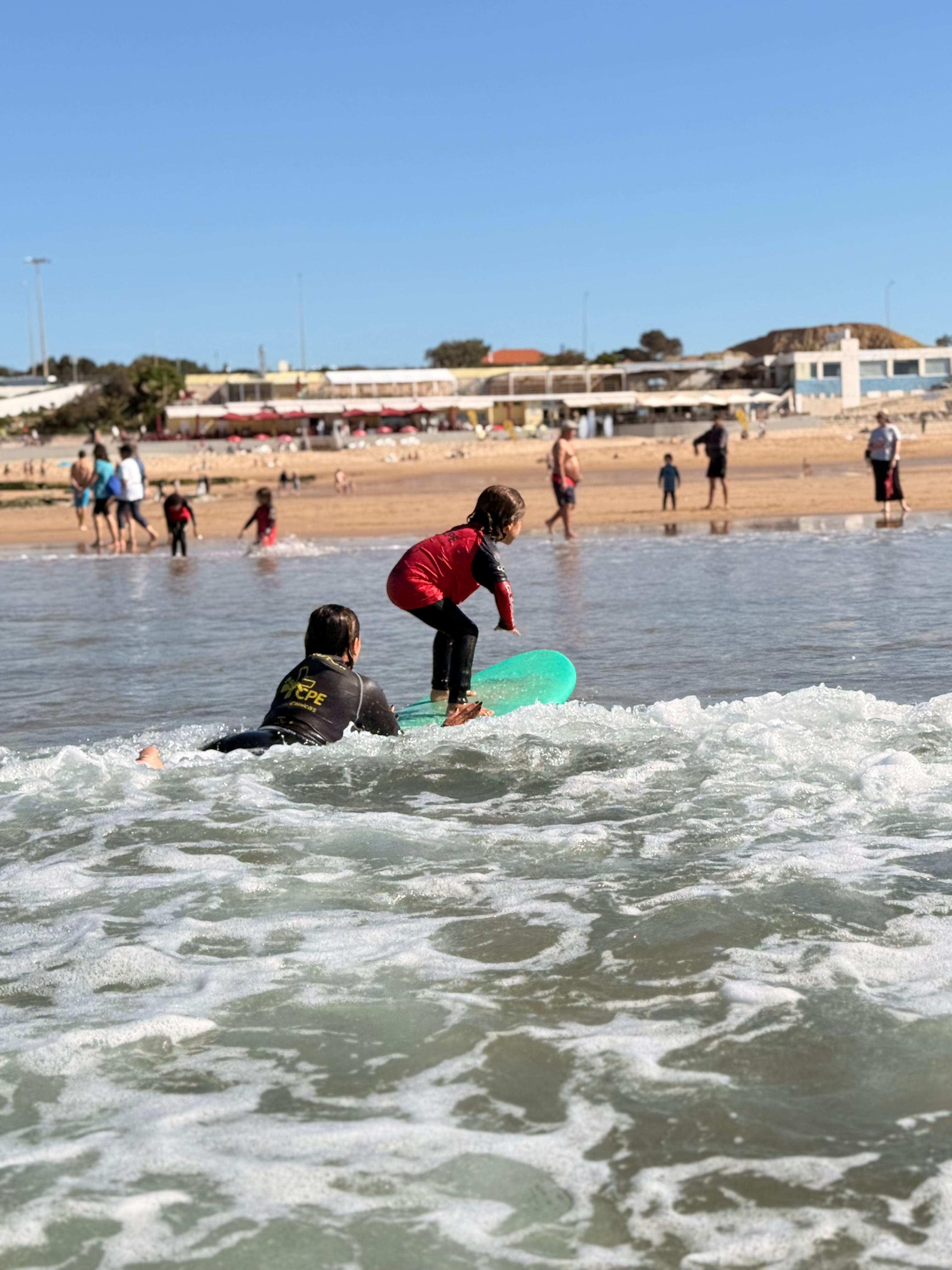 Criança a surfar com a praia ao fundo