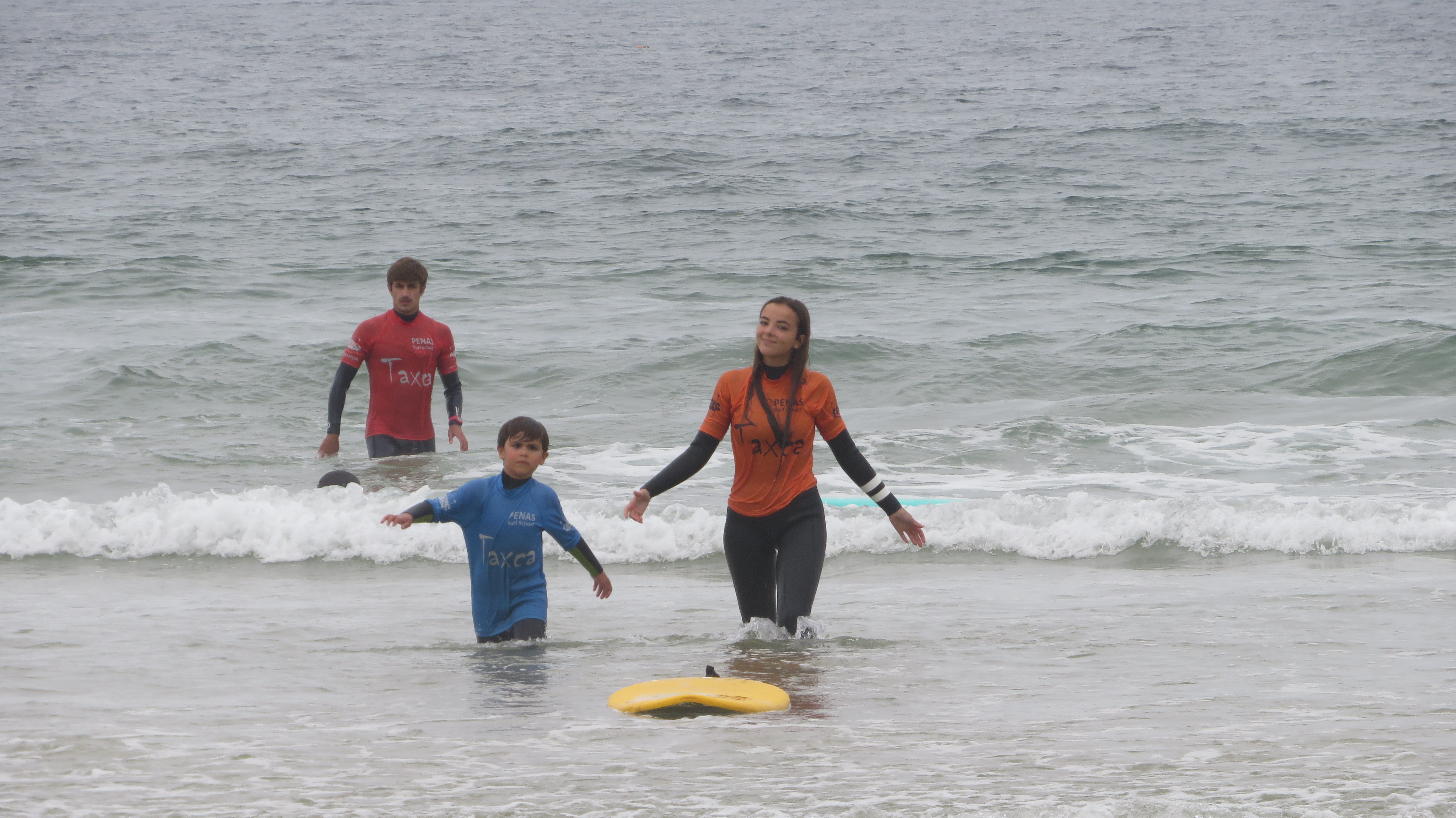 Instrutora Kids Care com criança no mar — aula de surf